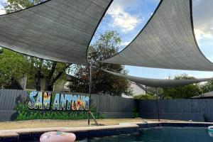 Una piscina con una sombrilla delante de una valla. en Great home, great location at a great price!, en San Antonio
