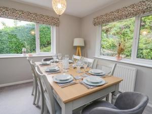 a dining room with a table and chairs and windows at Lleifior in Dolgellau
