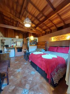 a bedroom with a large red bed and a kitchen at Pousada Anecuém in Monte Verde