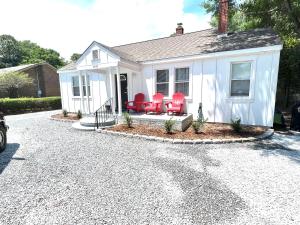 een wit huis met rode stoelen op de oprit bij The Absolute Best Home Away From Home Pet Friendly!!! in Wilmington