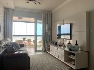 a living room with a couch and a flat screen tv at Apartamento Beira Mar in Arroio do Silva