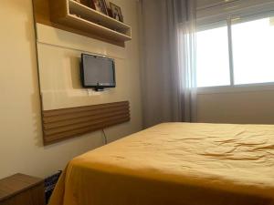 a bedroom with a bed and a tv on a wall at Apartamento Beira Mar in Arroio do Silva