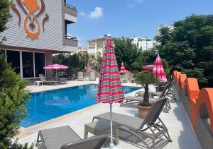 einen Pool mit Stühlen und Sonnenschirmen neben einem Gebäude in der Unterkunft Lara Olympos Hotel in Antalya