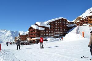 a group of people skiing in the snow in front of a hotel at Résidence Montana Premier in Val Thorens