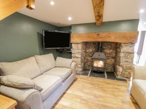 a living room with a couch and a stone fireplace at Pen Y Bont Ucha in Llandudno Junction