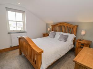 a bedroom with a wooden bed and a window at Pen Y Bont Ucha in Llandudno Junction