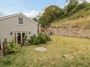 a house with a yard next to a stone wall at Pen Y Bont Ucha in Llandudno Junction