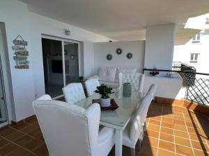 a dining room with a table and white chairs at MI CAPRICHO, Beach Front Apartment P14 3ºB in Mijas Costa