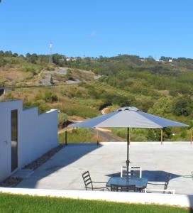 eine Terrasse mit einem Sonnenschirm, Stühlen und einem Tisch in der Unterkunft Villa Santos in São Gregório