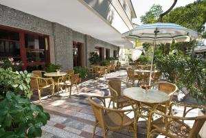 un patio esterno con tavoli, sedie e ombrellone di Hotel Capinera a Rimini