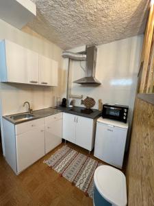 Residencial Mira-Mar في بينيش: مطبخ بدولاب بيضاء ومغسلة وموقد