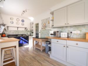 a kitchen with white cabinets and a wooden table at Penylan in Seaton