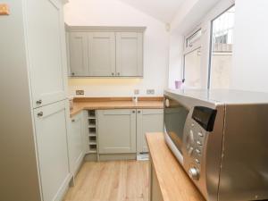 a kitchen with white cabinets and a stainless steel appliance at Fair Mead Cottage in Saltash