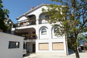 une maison blanche avec un balcon et un arbre dans l'établissement Rooms with a parking space Lovran, Opatija - 2302, à Lovran