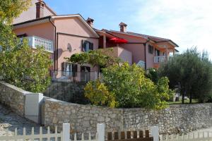 a house behind a stone wall with a fence at Apartments by the sea Duga Luka - Prtlog, Labin - 2358 in Drenje