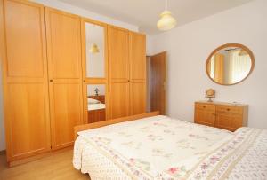 a bedroom with a bed and wooden cabinets and a mirror at Apartment Rabac 2340a in Rabac