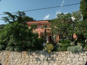 a house with a stone wall and trees at Apartment Crikvenica 2354e in Crikvenica