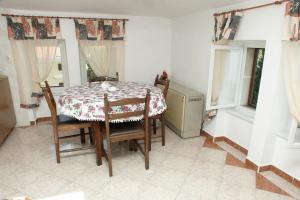 ein Esszimmer mit einem Tisch, Stühlen und Fenstern in der Unterkunft Apartments by the sea Lovran, Opatija - 2351 in Lovran