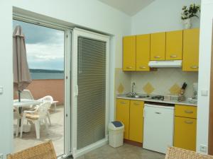 a kitchen with yellow cabinets and a view of a patio at Apartment Crikvenica 2354e in Crikvenica