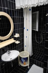 een zwart betegelde badkamer met een wastafel en een spiegel bij Apartments with a parking space Smrika, Kraljevica - 2365 in Šmrika