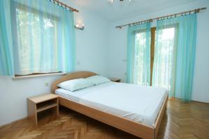 a bedroom with a large bed with blue curtains at Apartments with a parking space Povile, Novi Vinodolski - 2398 in Povile