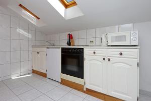 a kitchen with white cabinets and a stove and microwave at Apartment Selce 2362a in Selce