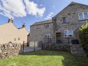 an old stone house with a stone wall at Woodgate in Buxton