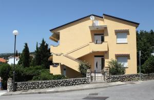 a yellow house with a stone wall at Apartments with a parking space Selce, Crikvenica - 2361 in Selce