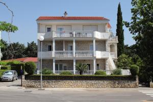 a white house with a balcony on a stone wall at Apartments by the sea Selce, Crikvenica - 2392 in Selce