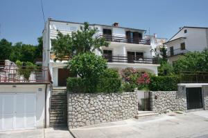 a white apartment building with a stone wall at Apartments and rooms with parking space Dramalj, Crikvenica - 2386 in Dramalj