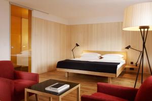 a bedroom with a bed and two chairs and a table at Hotel Gasthof Krone in Hittisau