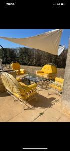 un groupe de chaises jaunes, d'une table et d'un parasol dans l'établissement Les Olivades, à Vauvert