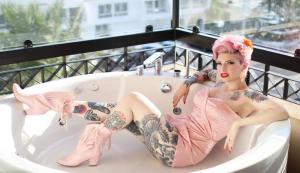 a woman with tattoos sitting in a bath tub at Brown Eilat a member of Brown Hotels in Eilat