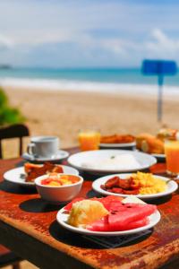 - une table avec des assiettes de nourriture sur la plage dans l'établissement Pousada Xalés de Maracaípe, à Porto de Galinhas