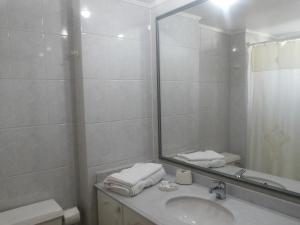 Baño blanco con lavabo y espejo en Apart Hotel Carampangue en Valdivia