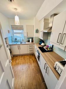 a small kitchen with white cabinets and wooden floors at Ridge Cottage Portrush in Portrush