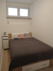 uma cama num pequeno quarto com duas janelas em Runa em Zagreb