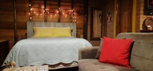 une chambre avec un lit, une chaise et un canapé dans l'établissement Chalé Caminho da Montanha, à Gonçalves