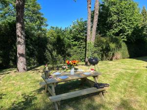 - une table de pique-nique dans l'herbe avec des fleurs dans l'établissement Le Manoir des Lys, à Tilly-sur-Seulles