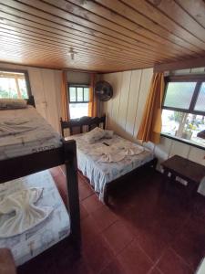 una stanza con due letti e due finestre di Pousada Trilha do Farol a Ilha do Mel