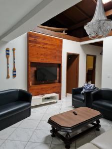 uma sala de estar com um sofá e uma televisão em Maika'i Pousada no Balneário Camboriú