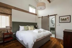 a bedroom with a large bed with white sheets at Linseed Barn- Stamford Holiday Cottages in Stamford