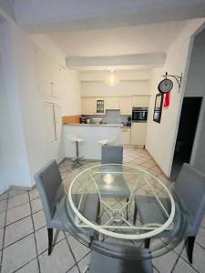 une chambre avec une table et des chaises en verre ainsi qu'une cuisine dans l'établissement Au cœur de Cannes, à l’angle de la rue d’Antibes, à Cannes