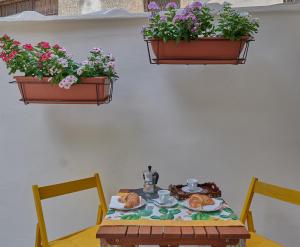 una mesa con dos sillas y dos plantas en la pared en Corte Laura nel cuore di Maglie, en Maglie