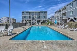 a swimming pool with chairs and a building at Waterfront Ocean Isle Beach Condo with Balcony! in Ocean Isle Beach