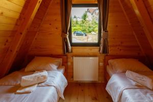 two beds in a room with a window at Zlatarski čardaci in Nova Varoš