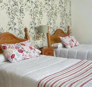 2 camas en un dormitorio con papel pintado con motivos florales en Hotel Corona de Atarfe en Atarfe