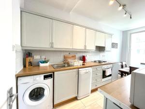 a kitchen with white cabinets and a washer and dryer at South Bridge Apartment in Edinburgh