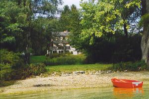 ein rotes Boot im Wasser in der Nähe eines Hauses in der Unterkunft Ferienhaus Haus am Ufer in Gaienhofen