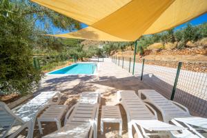 - un groupe de chaises et une piscine avec un parasol jaune dans l'établissement Cortijo El Chopo Almería, à Bayarque